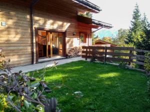 a wooden house with a yard next to a building at Chalet Banksia by Interhome in Ovronnaz