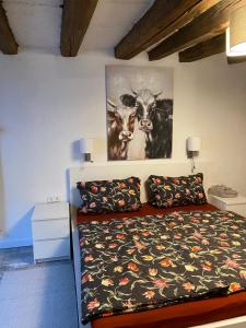 una camera con un letto e una foto di due mucche di Schöne Ferienwohnung Gewölbekeller Fachwerkhaus a Bacharach