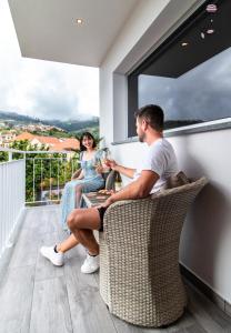 a man and a woman sitting on a balcony at La Chambre Rose in Ponta do Sol