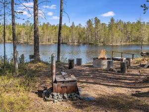 eine Feuerstelle neben einem See mit Bäumen in der Unterkunft Holiday Home Kiehtäjän virta by Interhome in Käylä