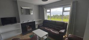 sala de estar con sofá de cuero y ventana en Knockalt Cottage en Moville
