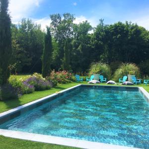 una piscina en un patio con sillas y árboles en Manoir le Mingreaud Chambres d'hôtes, en Sainte-Gemme-la-Plaine