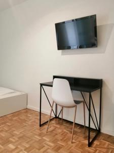 einen schwarzen Schreibtisch mit einem weißen Stuhl und einem TV an der Wand in der Unterkunft Appartement 509 in Klagenfurt am Wörthersee