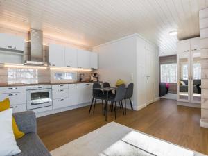 uma cozinha com armários brancos e uma mesa e cadeiras em Holiday Home Kiviranta by Interhome em Korpilahti