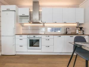uma cozinha com armários brancos e um frigorífico em Holiday Home Kiviranta by Interhome em Korpilahti
