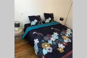 a bed with a black blanket with flowers on it at George V - Enjoy the view of the sea channel in Les Sables-dʼOlonne