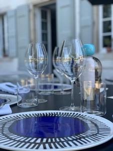 four wine glasses sitting on a table with a plate at Château de la Bousquetarie in Lempaut