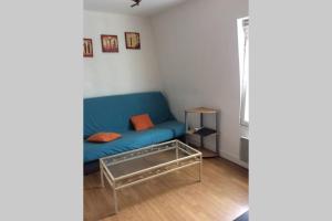 a living room with a blue couch and a table at Votre appartement à 200m de la plage in Ouistreham
