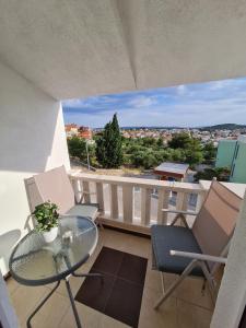 a balcony with a glass table and chairs on a balcony at Apartmani Levarda in Trogir
