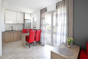 a kitchen and dining room with red chairs and a table at Apartament Red Mielno in Mielno