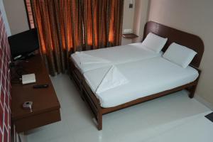 a small bedroom with a bed and a table at SANGEETHA TOURIST HOME in Trivandrum