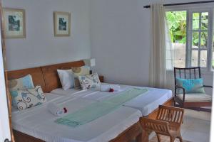 a bedroom with a large bed with a chair and a window at Petit Baie Chalets in Au Cap