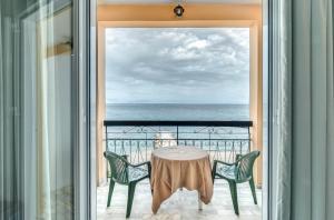 un tavolo e sedie su un balcone con vista sull'oceano di Eros Beach Hotel a Benitses