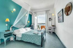 a bedroom with a bed and a desk and a window at Eros Beach Hotel in Benitses
