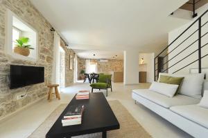 a living room with a white couch and a tv at Villa Mira with a heated pool and a sea view in Božava