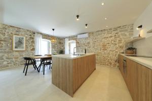 a kitchen and dining room with a stone wall at Villa Mira with a heated pool and a sea view in Božava