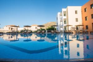 a large swimming pool with buildings and umbrellas at Mitos Village in Hersonissos