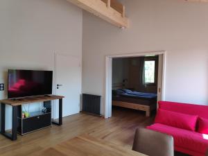 a living room with a red couch and a bedroom at Ferienwohnungen und Zimmer in Reutlingen-Gönningen in Reutlingen