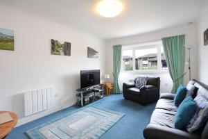 a living room with a couch and a tv at Ideal Central Edinburgh location with free on-site private parking in Edinburgh