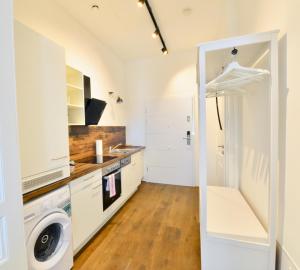 cocina con armarios blancos, lavadora y secadora en Charming Studio in Servitenviertel II, en Viena