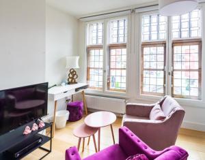sala de estar con muebles de color púrpura y TV en Antwerp old town appartment, en Amberes