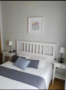 ein Schlafzimmer mit einem weißen Bett mit zwei Tischen und zwei Lampen in der Unterkunft Málaga Centro in Málaga