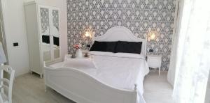 uma cama branca num quarto branco com papel de parede em Daniela em Policastro Bussentino