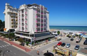 - un grand bâtiment blanc dans une rue à côté de l'océan dans l'établissement Hotel Kent, à Riccione