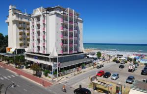a large white building on a street next to the ocean at Hotel Kent in Riccione