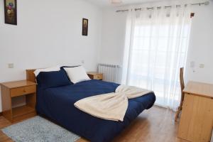 a bedroom with a blue bed with a desk and a window at Casa da Praia in Vila Praia de Âncora