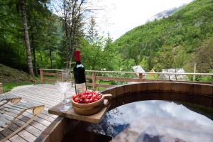 una botella de vino y un tazón de manzanas en un puente en Camp Korita, en Soča