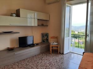 a living room with a tv and a large window at APPARTAMENTO CASA MARCO in Capoliveri