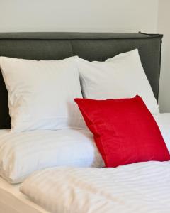 almohada roja en una cama con almohadas blancas en Charming Studio in Servitenviertel II, en Viena