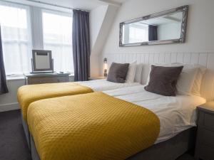 a bedroom with two beds with a yellow blanket at Carlton Hotel in Ilfracombe