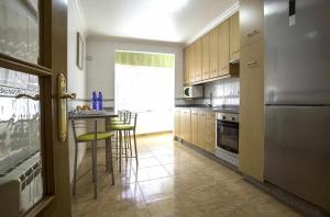 eine Küche mit einem Tisch und Stühlen sowie einem Kühlschrank in der Unterkunft Apartamento en Raxó in Pontevedra