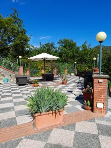 a patio with benches and an umbrella and plants at Bed&Breakfast Bella Vita in Moneglia