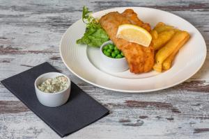 a plate of fish and french fries and a lemon slice at Carlton Hotel in Ilfracombe