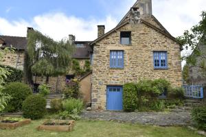 une ancienne maison en pierre avec une porte bleue dans l'établissement Gite du Pont Saint-Céneri-Le-Gérei dans les Alpes Mancelles, à Saint-Céneri-le-Gérei