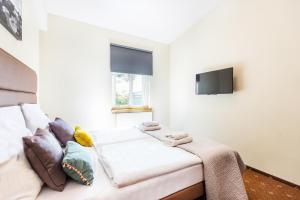 biała kanapa z poduszkami i telewizor w pokoju w obiekcie Aparthotel Old Town w Krakowie