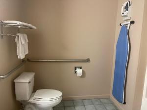 a bathroom with a toilet and a blue shower curtain at Highland Inn Denham Springs Baton Rouge East in Denham Springs +30 photos