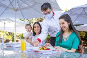 uma família sentada numa mesa com um homem a segurar um bebé em Hosteria Las Quintas Hotel Restaurante Bar em Cuernavaca