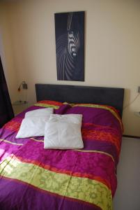 a bed with a colorful blanket and two pillows on it at AanHetGroteBos in Slenaken