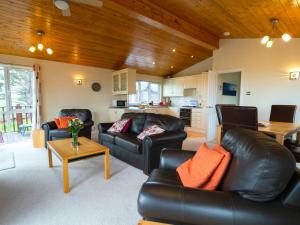 a living room with black leather furniture and a kitchen at Finest Retreats - Whitsand Bay Lodge in Torpoint