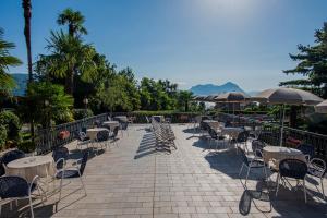 un patio con tavoli, sedie e ombrelloni di Hotel Alpi a Baveno