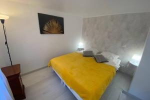 een slaapkamer met een bed met een gele deken bij SPA de charme 6 pers avec Jacuzzi & Sauna privatifs au coeur de ville - Esprit Coco in Mulhouse
