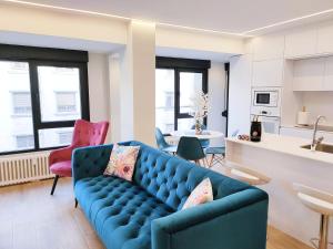 a living room with a blue couch and a kitchen at OVIEDO CENTRO SANTA CLARA PISO DE LUJO in Oviedo