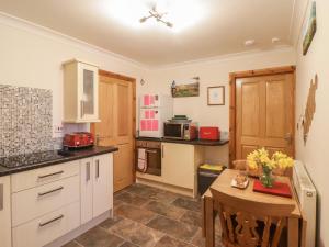 a kitchen with white cabinets and a wooden table at Swn Y Gwynt in Pont-Nedd-Fechan
