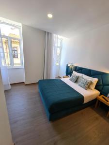 - une chambre avec un grand lit et une couverture bleue dans l'établissement Soldouro Train Suites, à Aveiro