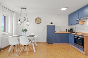 cocina con armarios azules, mesa y sillas en TTP Apartment 6 Friedrichshafen, en Friedrichshafen