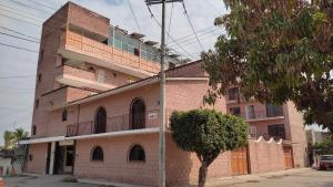 un edificio de ladrillo con un árbol delante de él en OYO Hotel Brisas Del Pacífico, en Puerto Vallarta